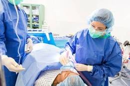 Two healthcare professionals administering anesthesia to patient