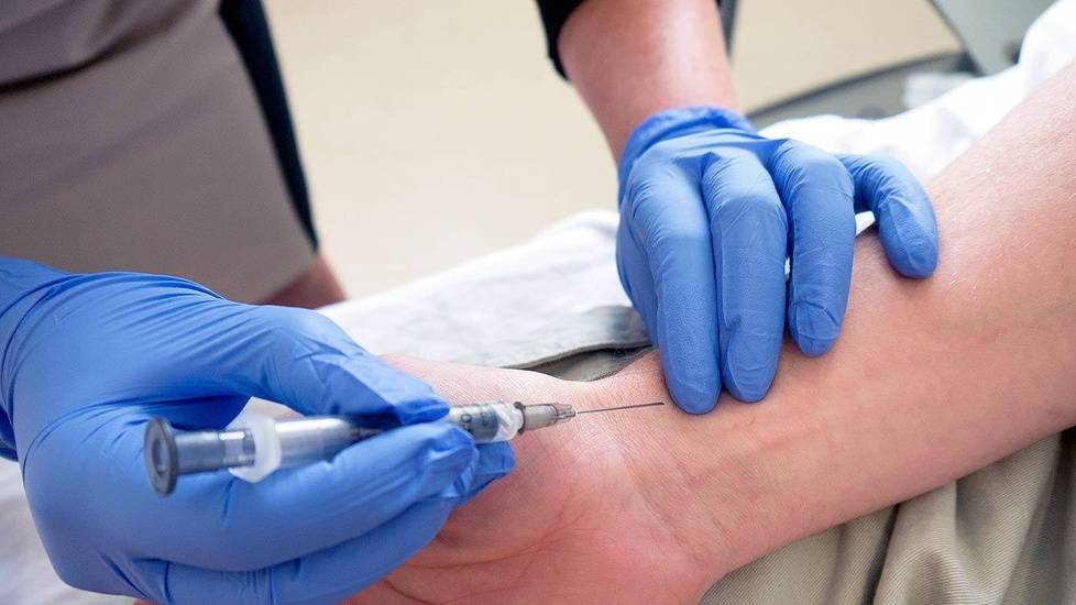 Nurse with gloves administering shot to patient's wrist